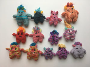 A group of colorful crocheted toys that resemble monsters